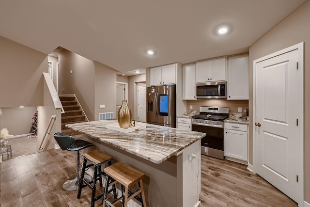 kitchen with white cabinets, light stone counters, and stainless steel appliances