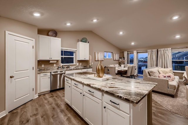 kitchen featuring white cabinets, light hardwood / wood-style flooring, dishwasher, a center island, and lofted ceiling