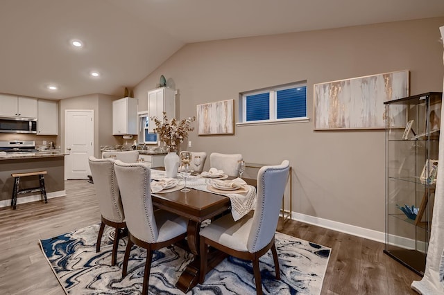 dining room with light hardwood / wood-style floors, vaulted ceiling, and sink