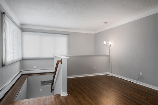 unfurnished room featuring baseboard heating, dark hardwood / wood-style flooring, and crown molding