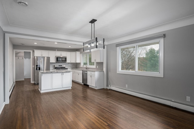 kitchen featuring white cabinetry, decorative light fixtures, a center island, baseboard heating, and appliances with stainless steel finishes