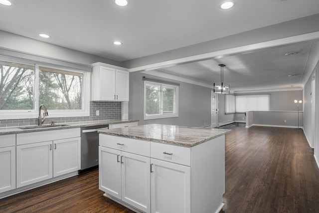 kitchen with white cabinetry, sink, a center island, stainless steel dishwasher, and light stone countertops