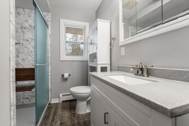 bathroom featuring hardwood / wood-style flooring, vanity, baseboard heating, walk in shower, and toilet