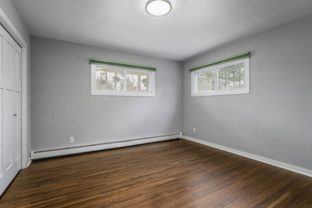 unfurnished bedroom with dark wood-type flooring, a closet, and baseboard heating