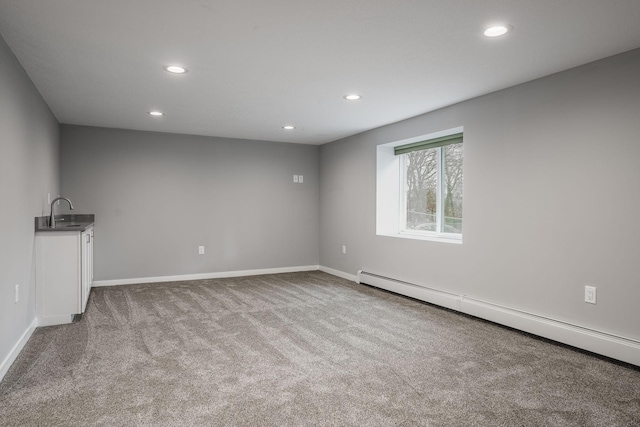 unfurnished room with sink, light colored carpet, and baseboard heating