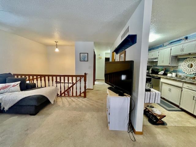 bedroom with a textured ceiling, light colored carpet, and sink