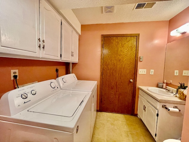 clothes washing area with sink, a textured ceiling, and independent washer and dryer