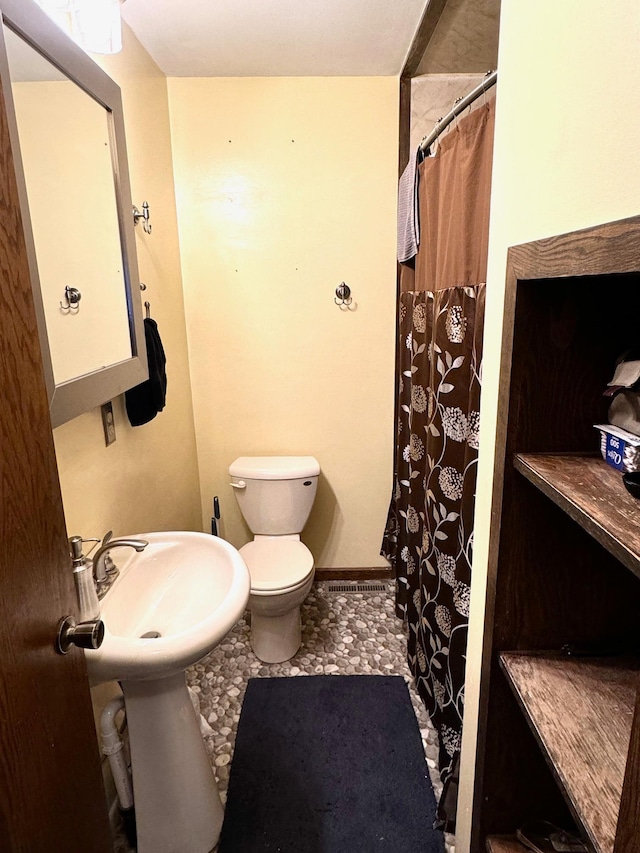 bathroom with toilet, curtained shower, and sink