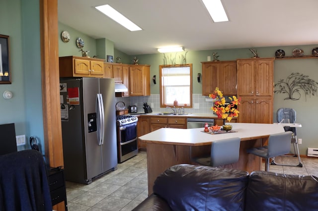 kitchen featuring a breakfast bar, tasteful backsplash, appliances with stainless steel finishes, a baseboard radiator, and sink