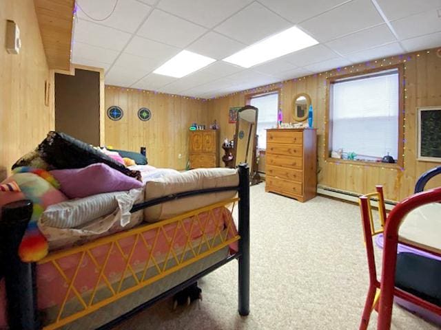 carpeted bedroom with a paneled ceiling and wood walls