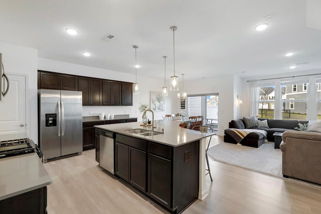 kitchen featuring sink, hanging light fixtures, a kitchen island with sink, dark brown cabinetry, and stainless steel appliances