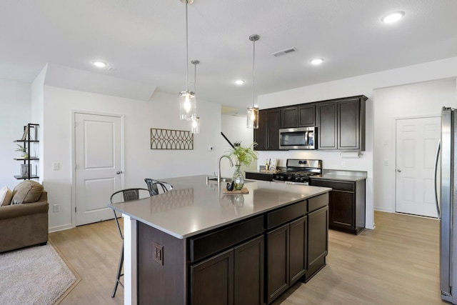 kitchen featuring appliances with stainless steel finishes, pendant lighting, an island with sink, sink, and a breakfast bar area