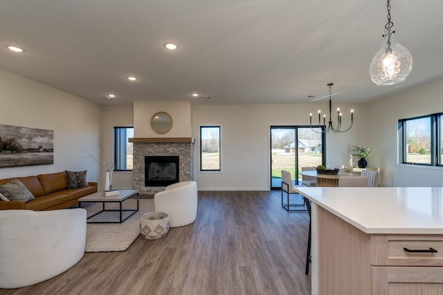 living room featuring a chandelier, hardwood / wood-style flooring, and a stone fireplace