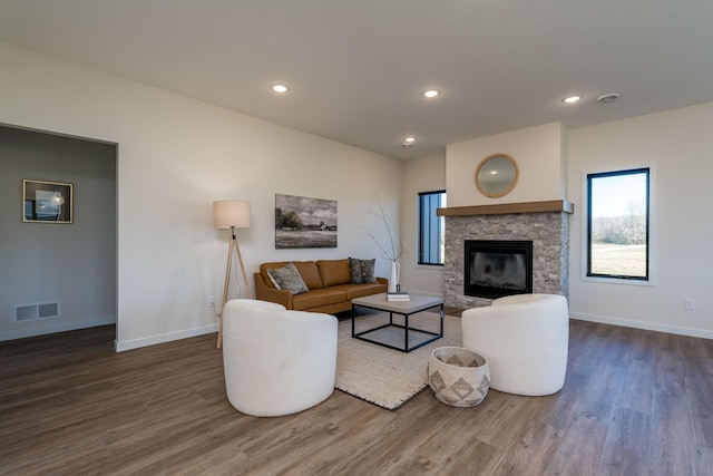 living room featuring a stone fireplace and dark hardwood / wood-style flooring