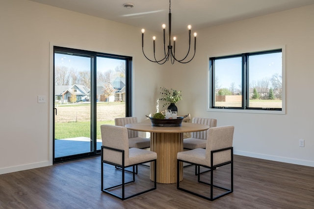 dining area with dark wood-type flooring, a wealth of natural light, and an inviting chandelier