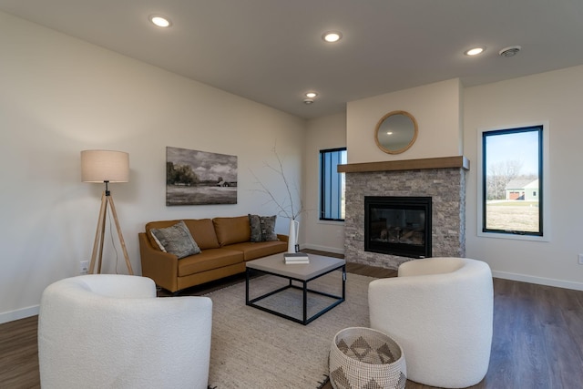 living room with a stone fireplace and dark wood-type flooring