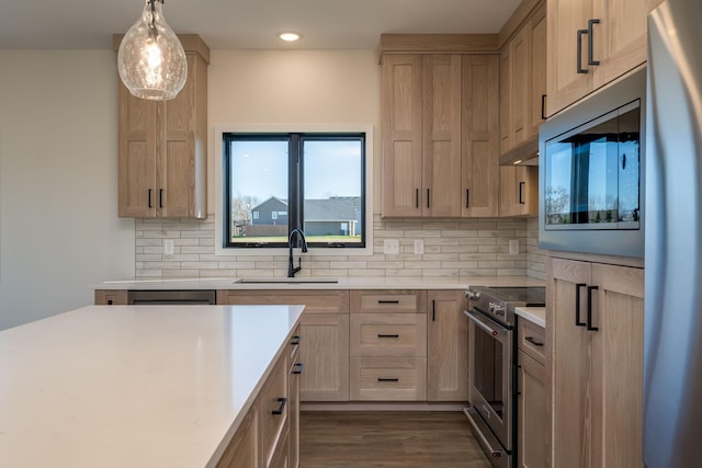 kitchen featuring appliances with stainless steel finishes, dark hardwood / wood-style flooring, tasteful backsplash, sink, and pendant lighting