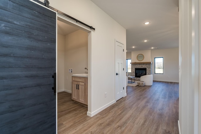 hallway with light wood-type flooring, a barn door, and sink