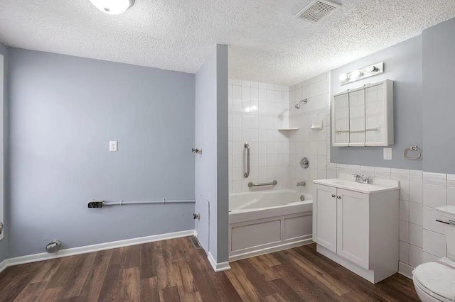 full bathroom with tile walls, wood-type flooring, a textured ceiling, and tiled shower / bath