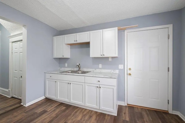 kitchen featuring a textured ceiling, white cabinetry, dark wood-type flooring, and sink