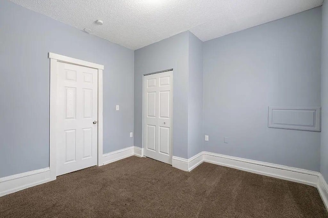 unfurnished bedroom with a closet, dark carpet, and a textured ceiling