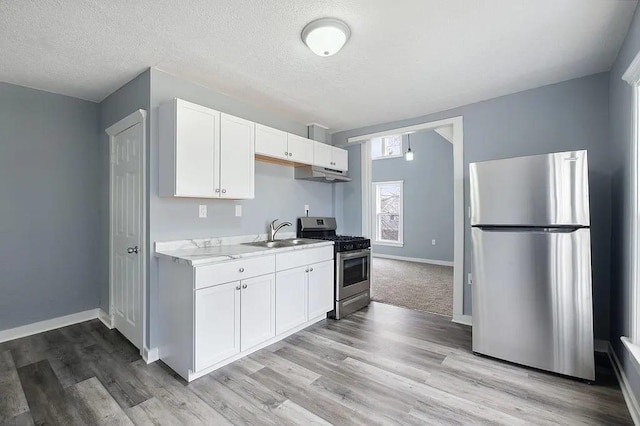 kitchen featuring appliances with stainless steel finishes, a textured ceiling, sink, light hardwood / wood-style flooring, and white cabinetry