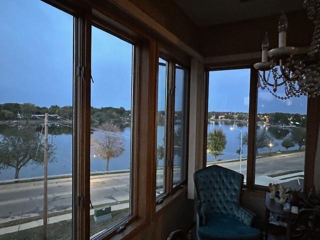 sunroom with a chandelier and a water view