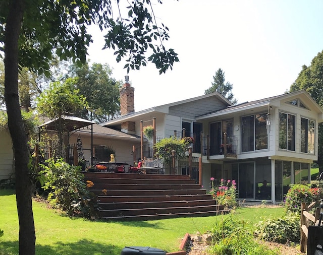 back of property with a lawn and a sunroom