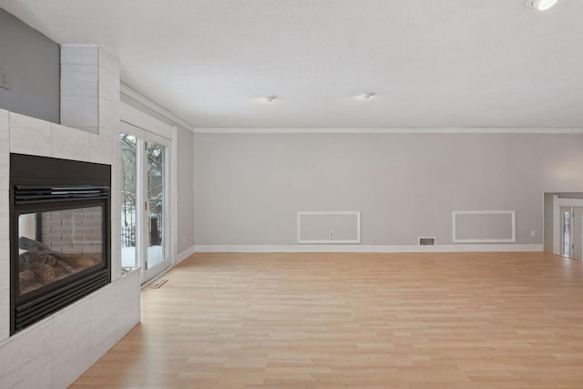 unfurnished living room with a fireplace, light wood-type flooring, and crown molding