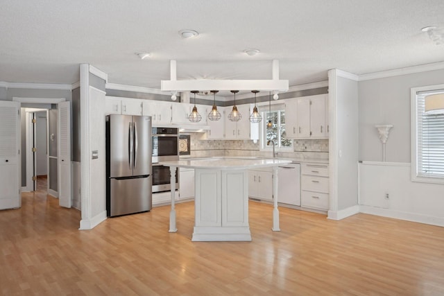 kitchen featuring backsplash, stainless steel appliances, a kitchen island, decorative light fixtures, and white cabinetry