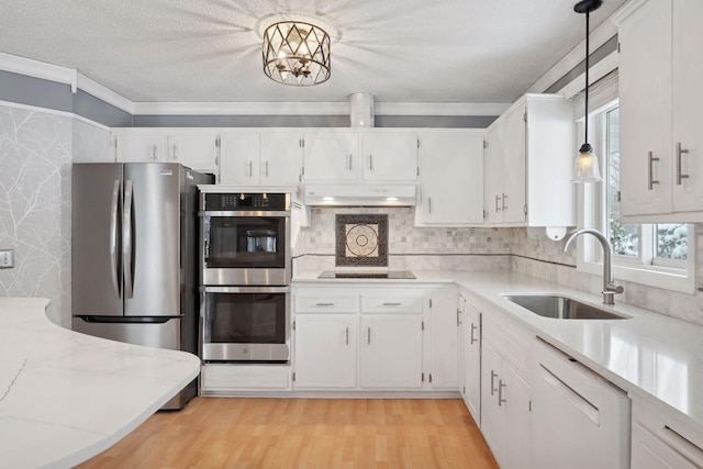 kitchen featuring white cabinetry, sink, decorative light fixtures, and appliances with stainless steel finishes