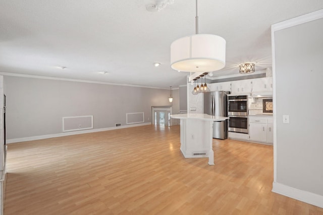 kitchen with white cabinetry, hanging light fixtures, appliances with stainless steel finishes, and ornamental molding