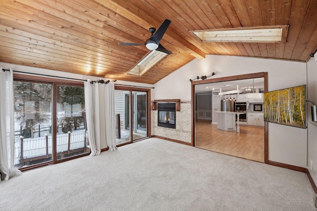 unfurnished living room with wooden ceiling, lofted ceiling with skylight, ceiling fan, a fireplace, and carpet floors