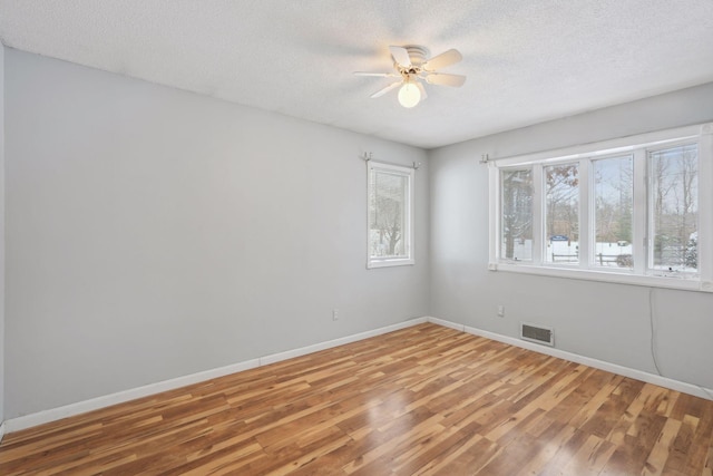 empty room with a textured ceiling, hardwood / wood-style flooring, and ceiling fan