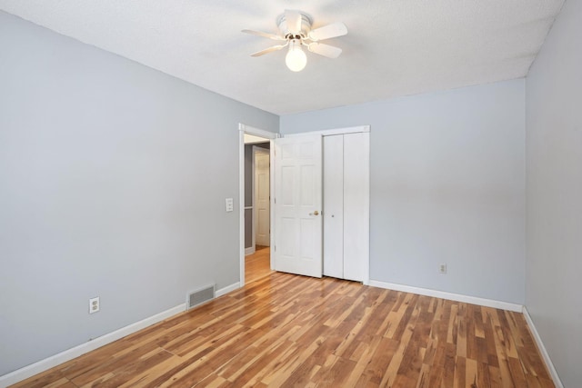 spare room with ceiling fan, light hardwood / wood-style floors, and a textured ceiling