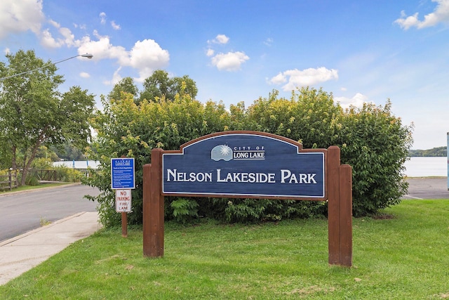 community sign featuring a yard and a water view