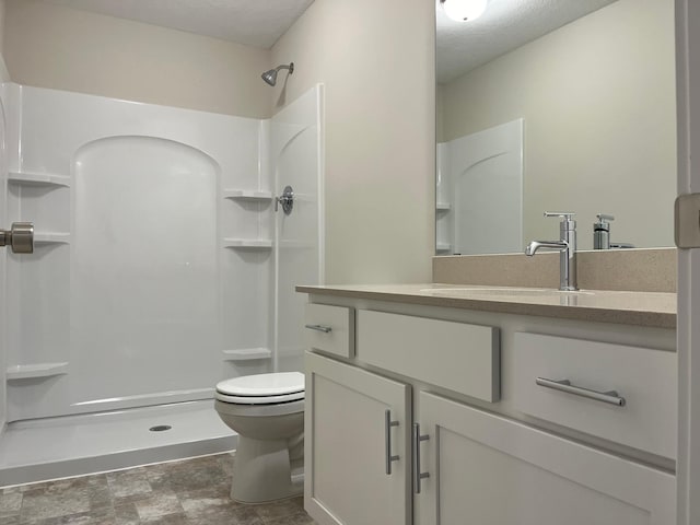 bathroom with a shower, vanity, a textured ceiling, and toilet