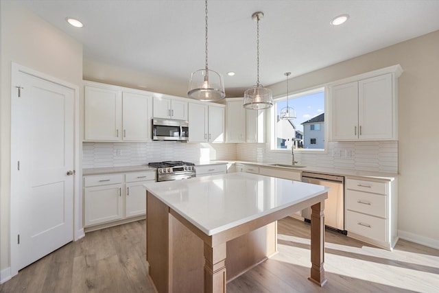 kitchen featuring white cabinetry, a center island, stainless steel appliances, and light hardwood / wood-style floors