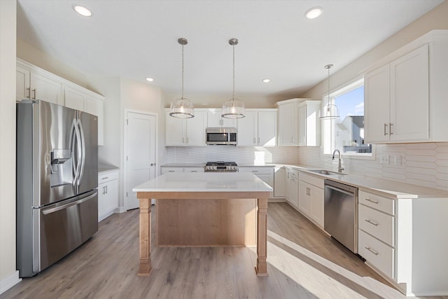 kitchen featuring stainless steel appliances, sink, light hardwood / wood-style flooring, white cabinets, and a center island