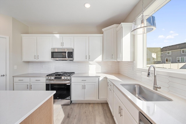 kitchen featuring backsplash, white cabinetry, light hardwood / wood-style flooring, and appliances with stainless steel finishes