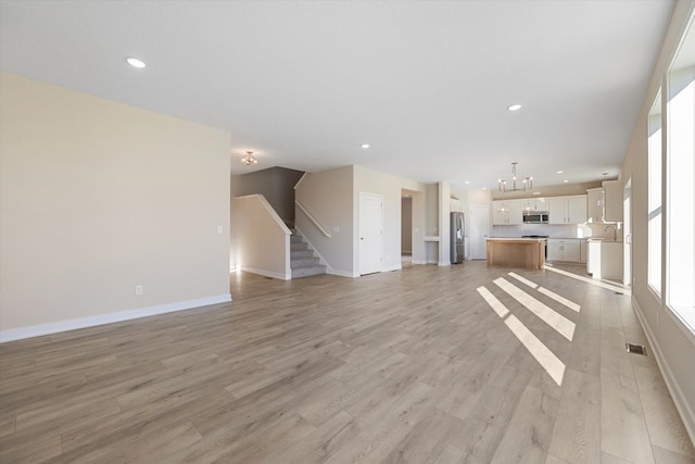 unfurnished living room featuring light hardwood / wood-style floors and a notable chandelier