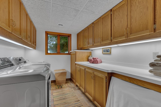 laundry room with washing machine and dryer, cabinets, and light wood-type flooring