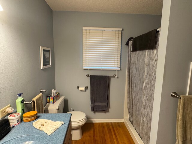 bathroom with a shower with curtain, a textured ceiling, hardwood / wood-style flooring, and toilet