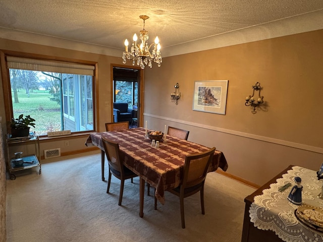 carpeted dining space with a notable chandelier and a textured ceiling