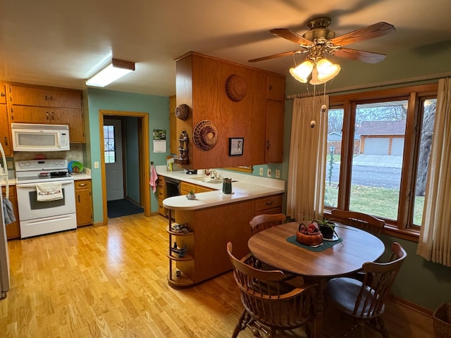 kitchen with kitchen peninsula, backsplash, white appliances, ceiling fan, and light hardwood / wood-style flooring