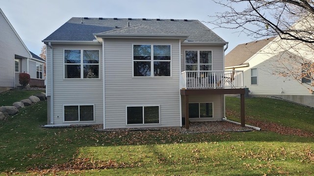 back of property featuring a yard and roof with shingles