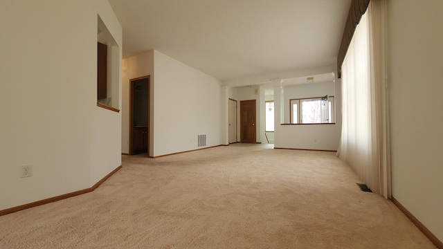 empty room featuring lofted ceiling, baseboards, visible vents, and light carpet