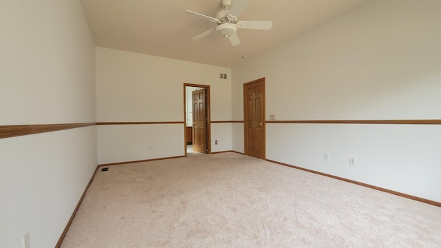 empty room with visible vents, baseboards, ceiling fan, light colored carpet, and vaulted ceiling