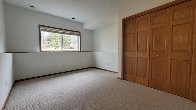 unfurnished bedroom featuring visible vents, baseboards, light colored carpet, and a closet