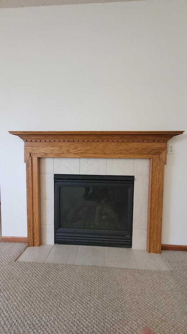 room details featuring baseboards, carpet, and a tiled fireplace